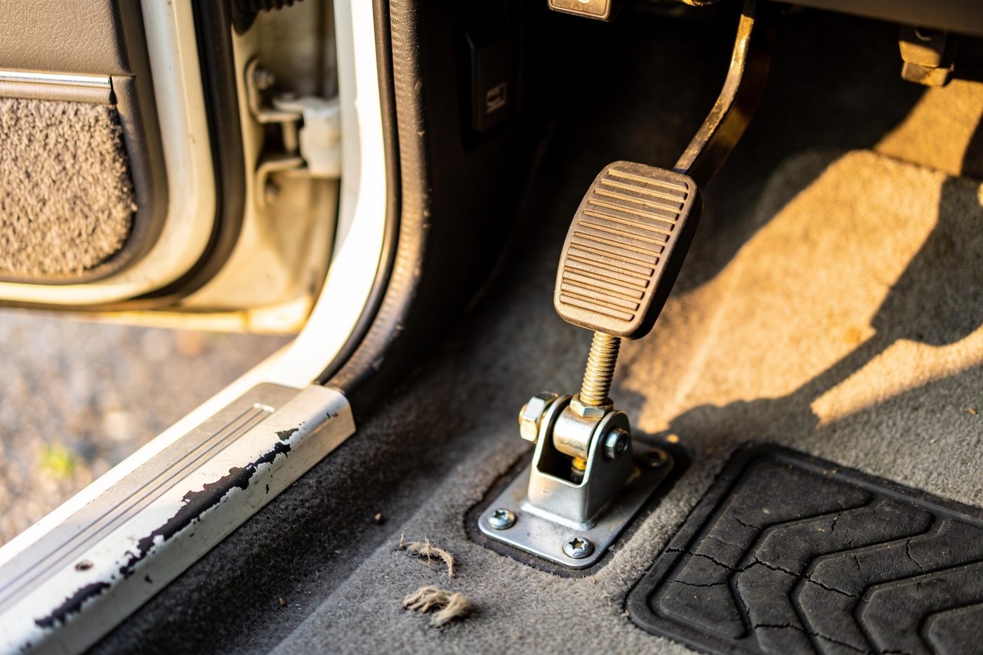 The instructor's brake pedal bolted into the passenger footwell above a worn rubber mat.